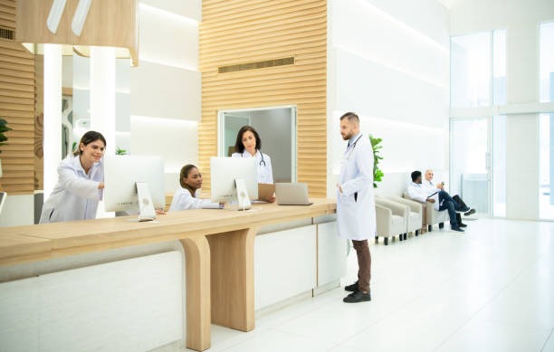 Recepción del consultorio médico con tres asistentes y un médico.