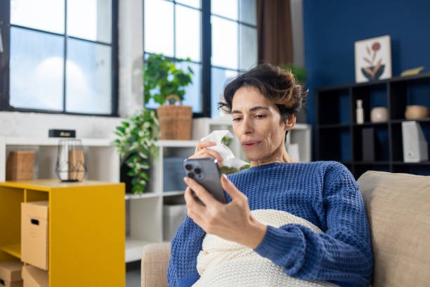 Mujer mirando su teléfono, sosteniendo un pañuelo