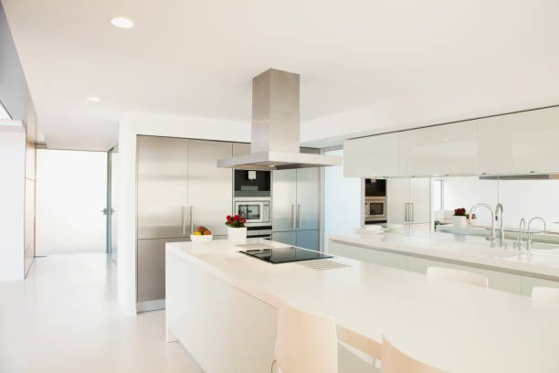 Cocina con muebles blancos, un ramo de rosas y un bol de fruta en la encimera.
