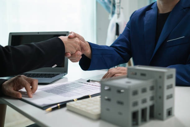 Apretón de manos de negocios sobre la mesa, computadora portátil sobre la mesa