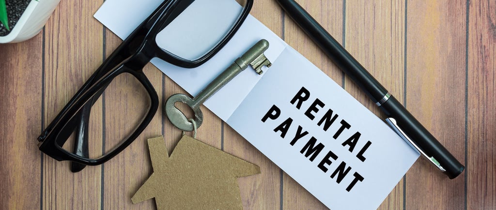 Rental payment text on notepad with house model and key on wooden desk