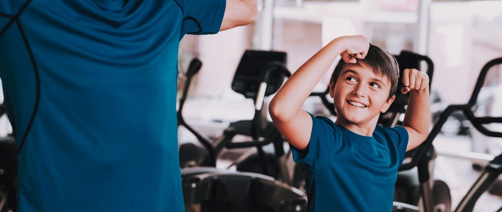 Un adulto e un bambino in palestra che mostrano i muscoli in modo giocoso, creando un momento divertente e motivante durante 