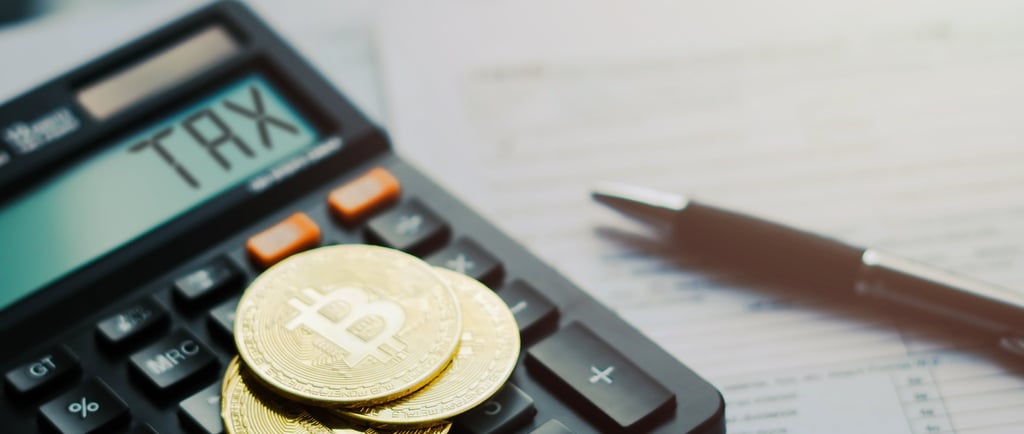 Gold Bitcoin coins on a calculator showing TAX for cryptocurrency tax filing and accounting.