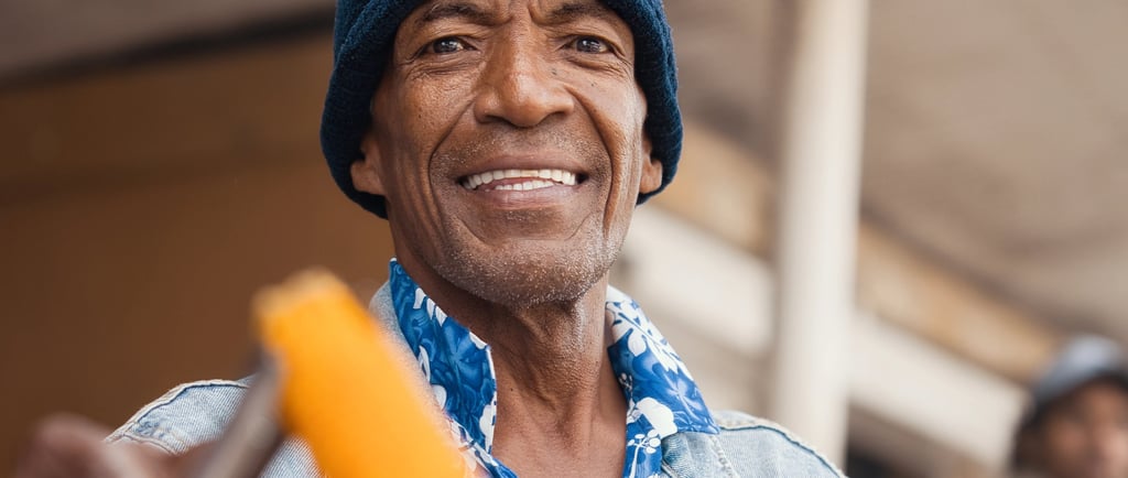 Man in a beanie hat smiling while holding roasted corn in Rodrigues.
