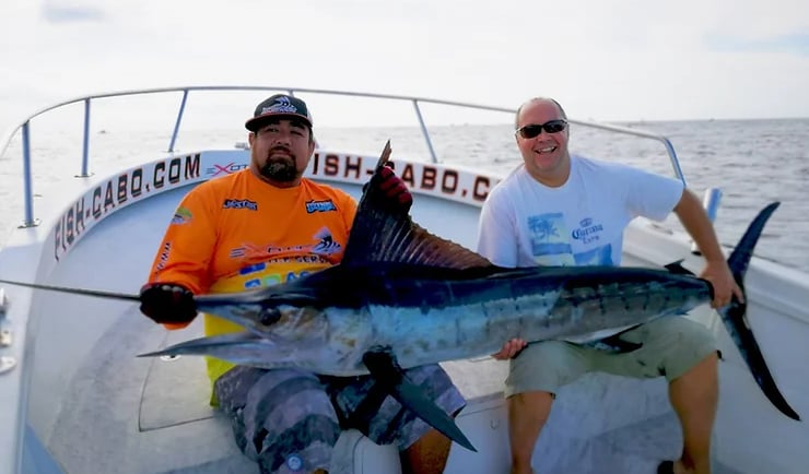 two men are holding a fish on a boat