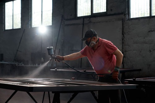 a man in a red shirt is spraying a metal table