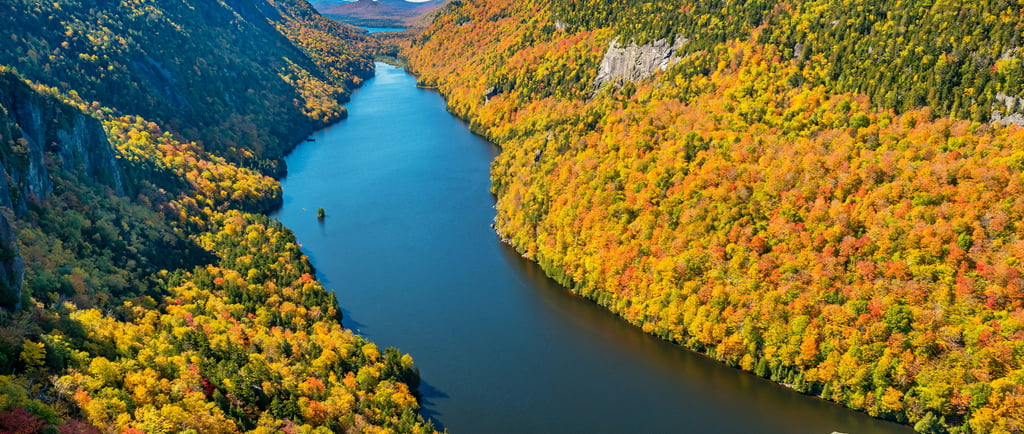 a river flowing through a valley with a mountain in the background