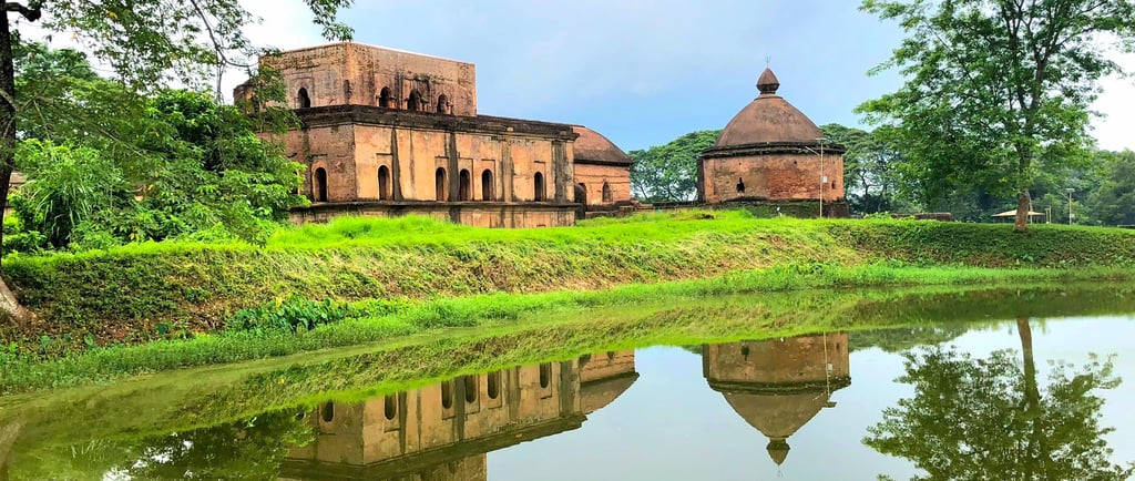 The historic Talatal Ghar and Ahom architecture reflected in a serene pond at Sivasagar, Assam.
