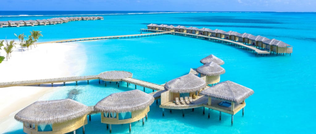 a beach resort with a pier and a dock, and floating villas in Maldives