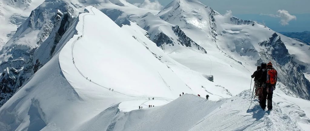 Group of hikers climbing the snowy ridge of Mount Breithorn towards the summit in the Swiss Alps
