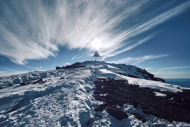 Summit of Mount Toubkal in Morocco with a metal marker and clouds in the background