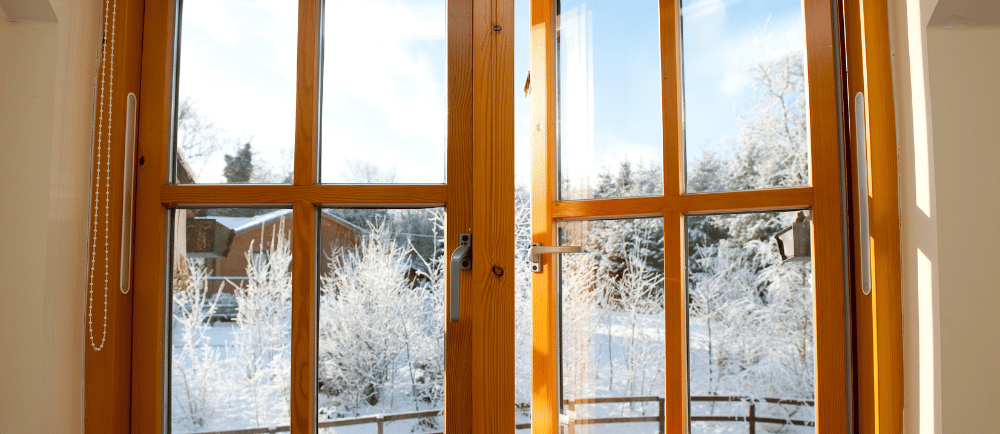 fenêtre en bois donnant sur un extérieur enneigée