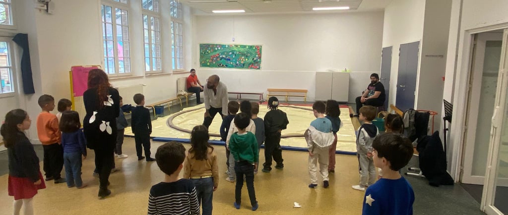 Des enfants font face a un homme placé qui s'adressent a eux, devant un dohyo