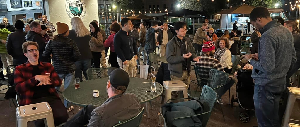 a group of people sitting at or standing around tables in a brewery