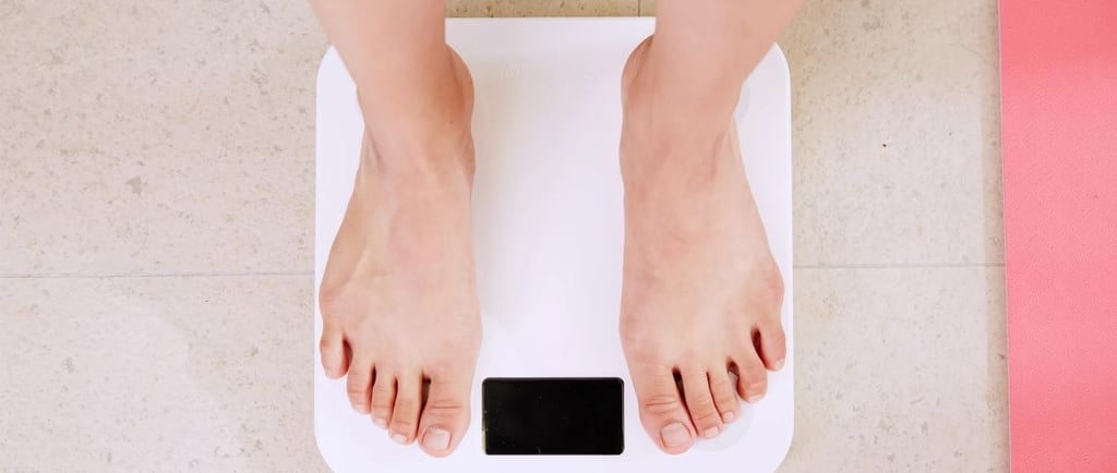 A person standing on a white digital bathroom scale for weight measurement and fitness tracking.