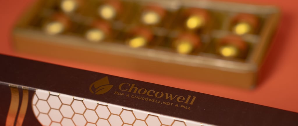 Box of Chocowell chocolate supplements with gold foil-wrapped balls in a gift tray.
