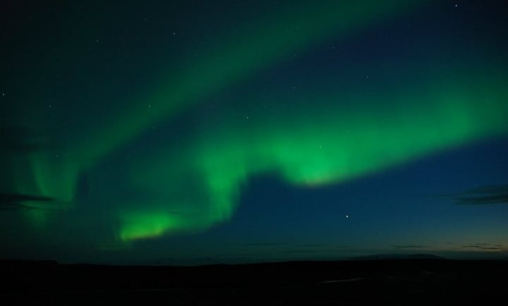 a green and blue sky with a bright green light in the background