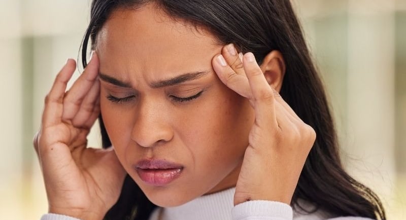 Mulher com dor de cabeça e facial, sintomas característicos de DTM e disfunção temporomandibular.
