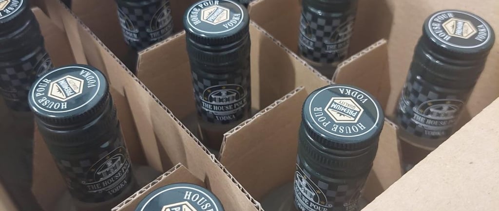Een doos met premium House Pour vodkaflessen, voorzien van zwarte etiketten en doppen, klaar voor di