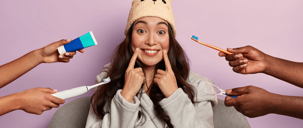 Mujer sonriente rodeada de herramientas de cuidado dental como cepillos de dientes, pasta y limpiado