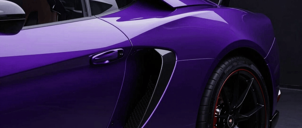 Side profile of a metallic purple luxury sports car featuring carbon fiber accents and black alloy wheels.