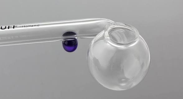 A clear glass vaporizer oil pipe with a round bulb bowl and a blue marble accent on a gray background.