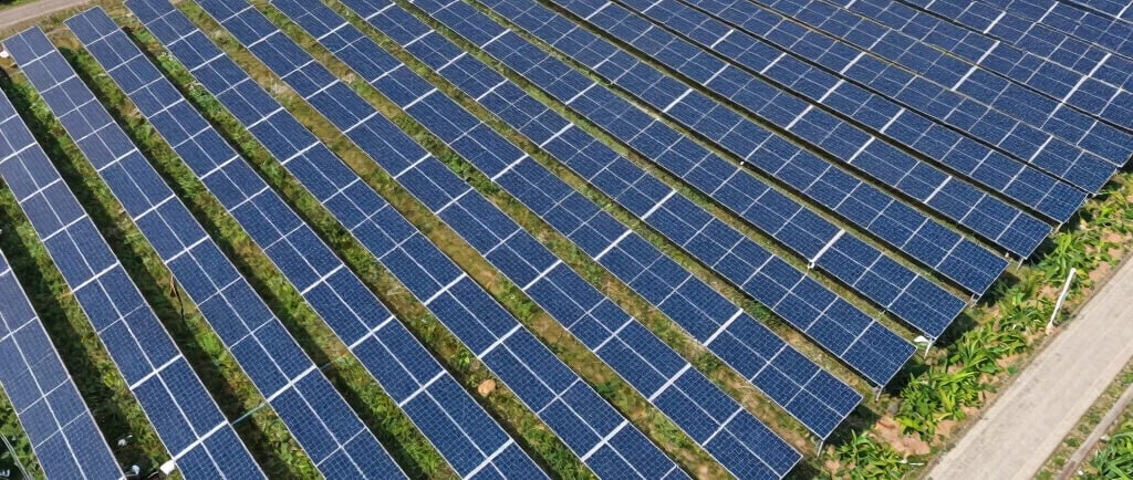 Aerial view of a large solar panel farm installation providing renewable energy in a rural landscape.