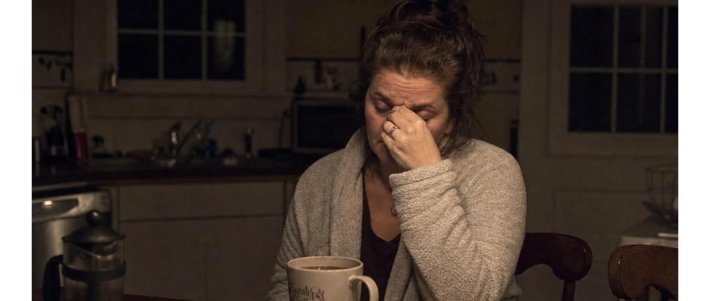 Exhausted family caregiver showing warning signs of caregiver burnout late at night in the kitchen