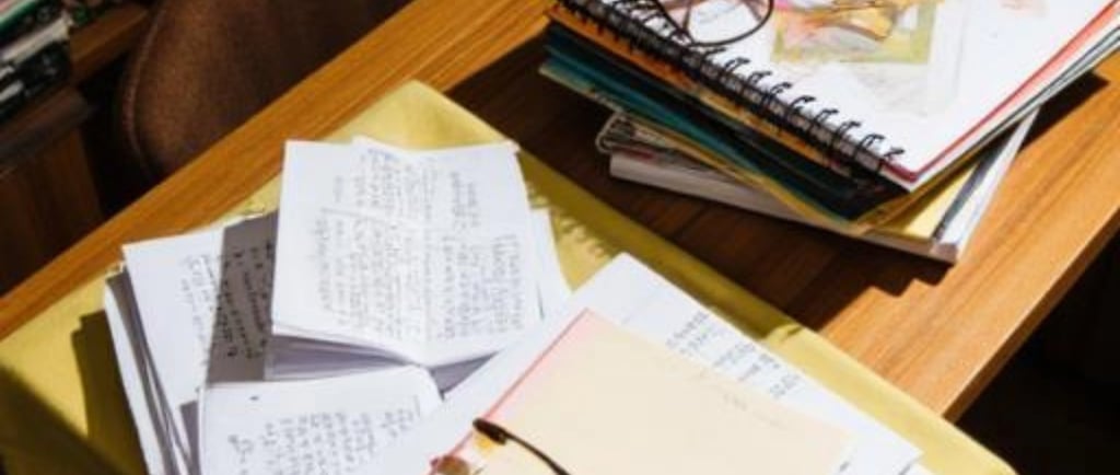 Escritorio con cuadernos, papeles y dos pares de anteojos en un ambiente de estudio.