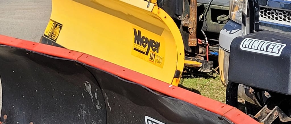 a picture of 4 plow blades attached to trucks includung the brands hiniker and meyer