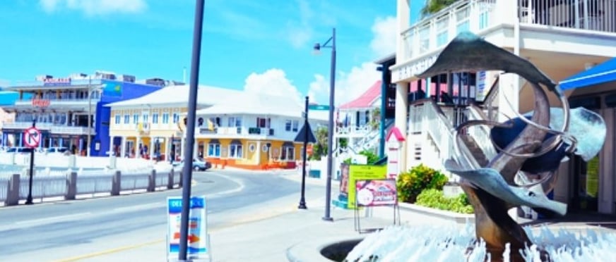 Rua de lojas e galerias em George Town, Ilhas Cayman, com fachadas coloridas e movimento de turistas.