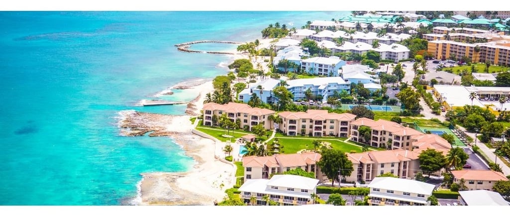 Vista aérea de Grand Cayman, destacando os grandes resorts à beira-mar e o litoral da ilha.