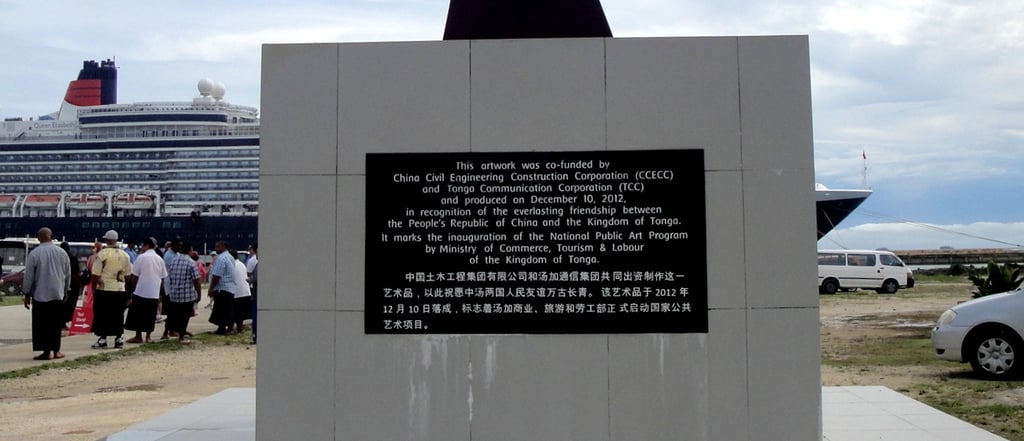 Navio de cruzeiro ancorado no porto de Nuku’alofa, Tonga, em frente a monumento histórico