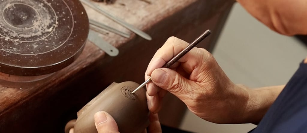 hand holding a tool, making a hole in the body of a teapot