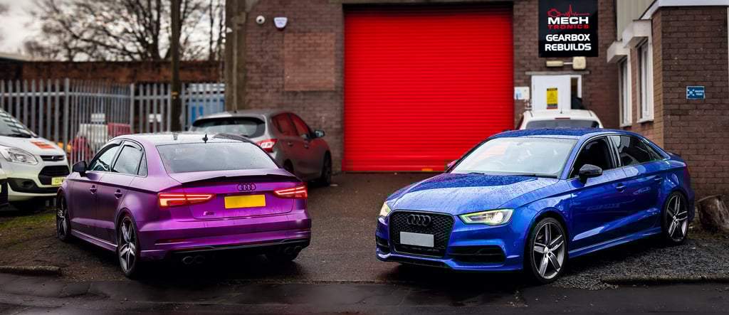 Purple and blue Audi performance cars parked outside a specialized gearbox rebuild garage.