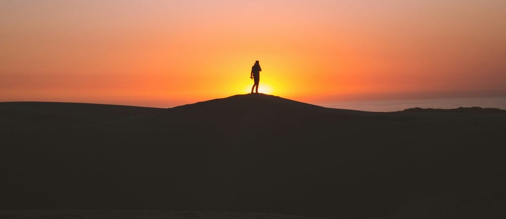 Lone hiker silhouetted at sunrise on desert hill, symbolizing solitude, strength, and new beginnings