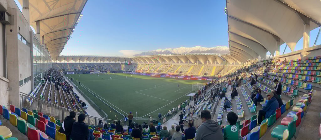 Estadio Bicentenario de La Florida, em Santiago do Chile, visto em dia claro com arquibancadas coloridas.