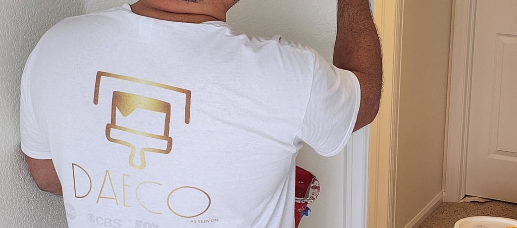 A professional painter using a brush to apply white Benjamin Moore paint to an interior wall corner.