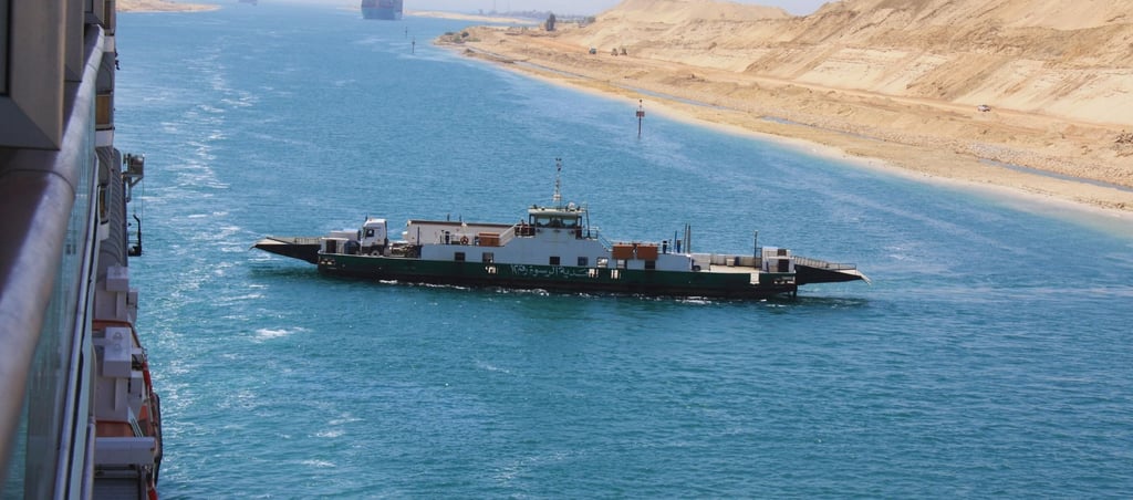 foto do navio navegando pelo canal de suez a frente de um barco local