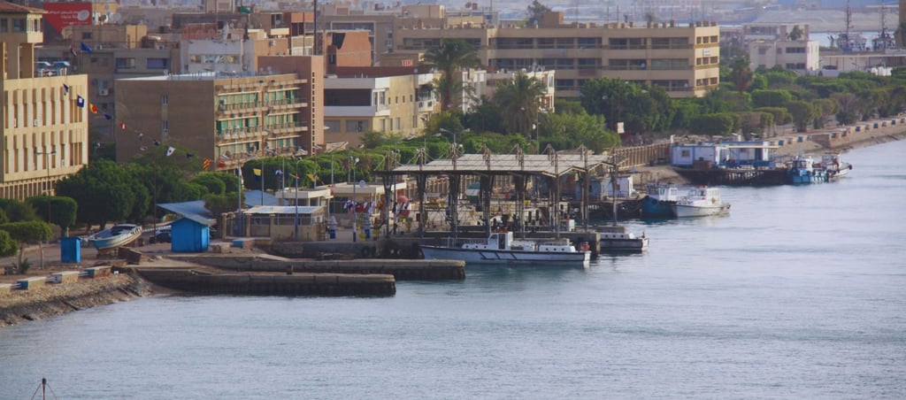 foto do navio navegando pelo canal de suez com vista para vilarejo