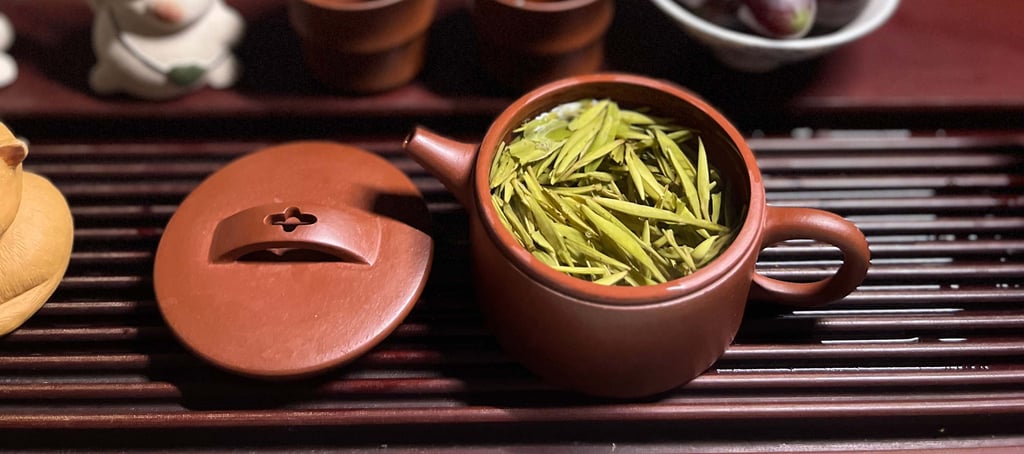 Tea set placed on a wooden tea tray, with green tea inside the teapot