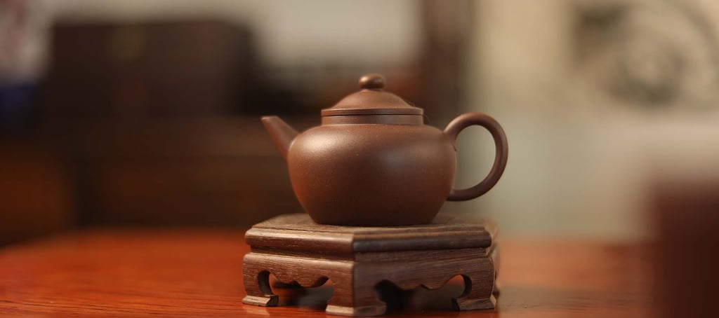 Dark brown teapot placed on a wooden stand