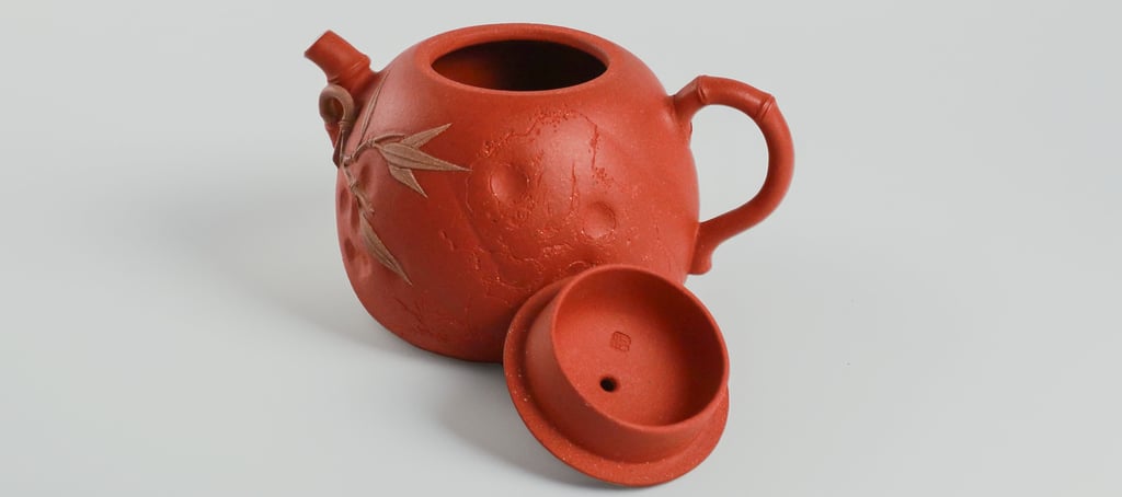 an teapot and its lid against a gray-white background.