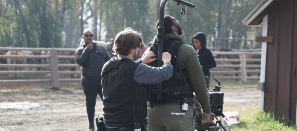 a man and woman are standing in a field working on an Easy Rig camera platform