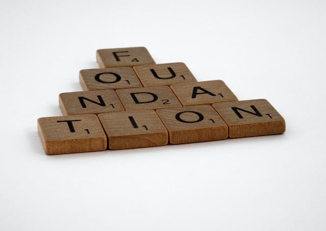 Scrabble letters spelling out the word foundation arranged in a pyramid shape on a white background