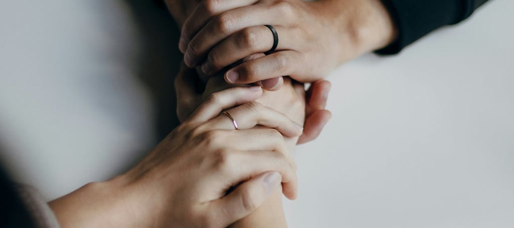 married Christian couple holding hands at a table, wedding rings visible
