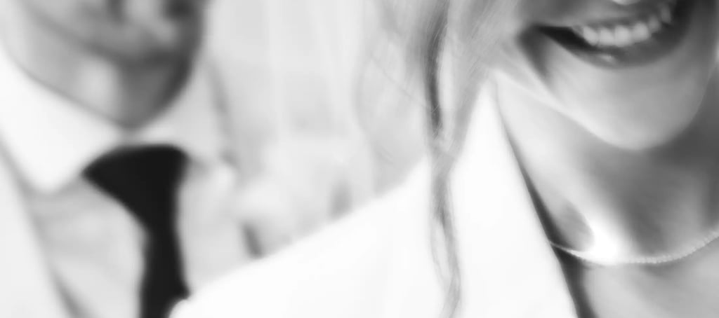 A blurred black and white close-up of a smiling bride and groom in wedding attire.