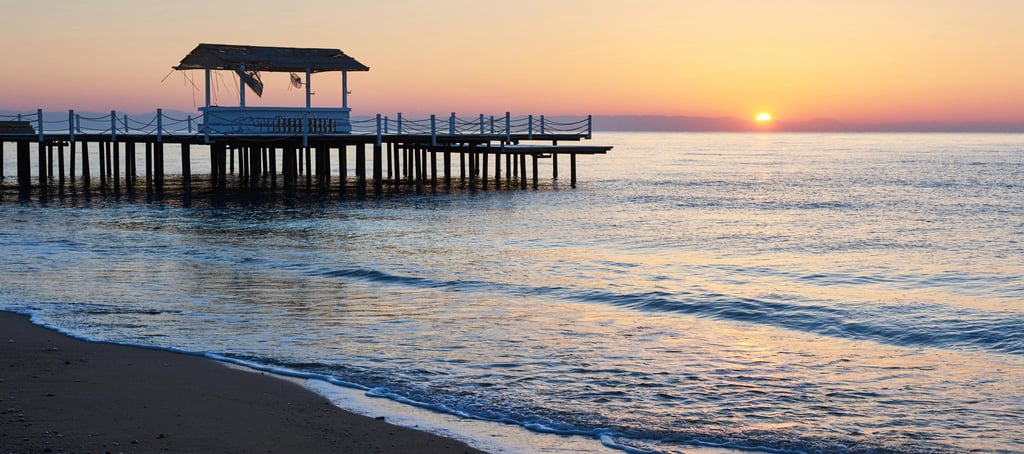 sunset on a beach next to a dock