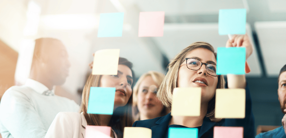 a group of people standing around a post - it notes on a sticky note pad