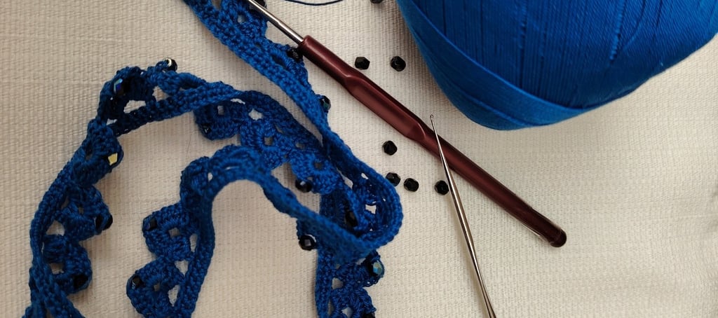 Collier crocheté dans un fil bleu très fin entouré de perles noir et deux crochet fin posé à coté